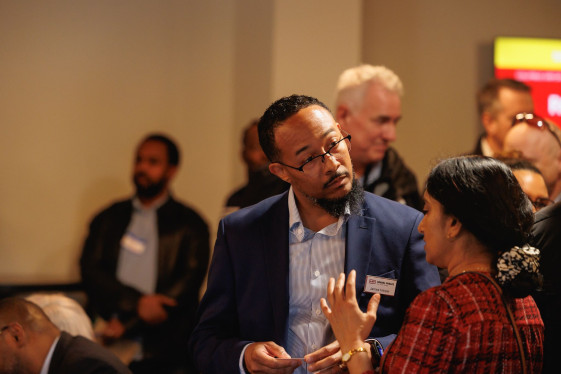 An individual from Hensel Phelps listens intently as a woman speaks with him at networking event.